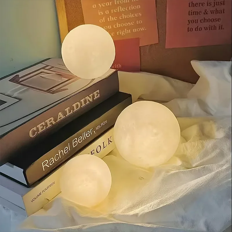 Cosmic Moon LED Book Light set with three glowing moon-shaped lamps in warm white light on books and fabric background