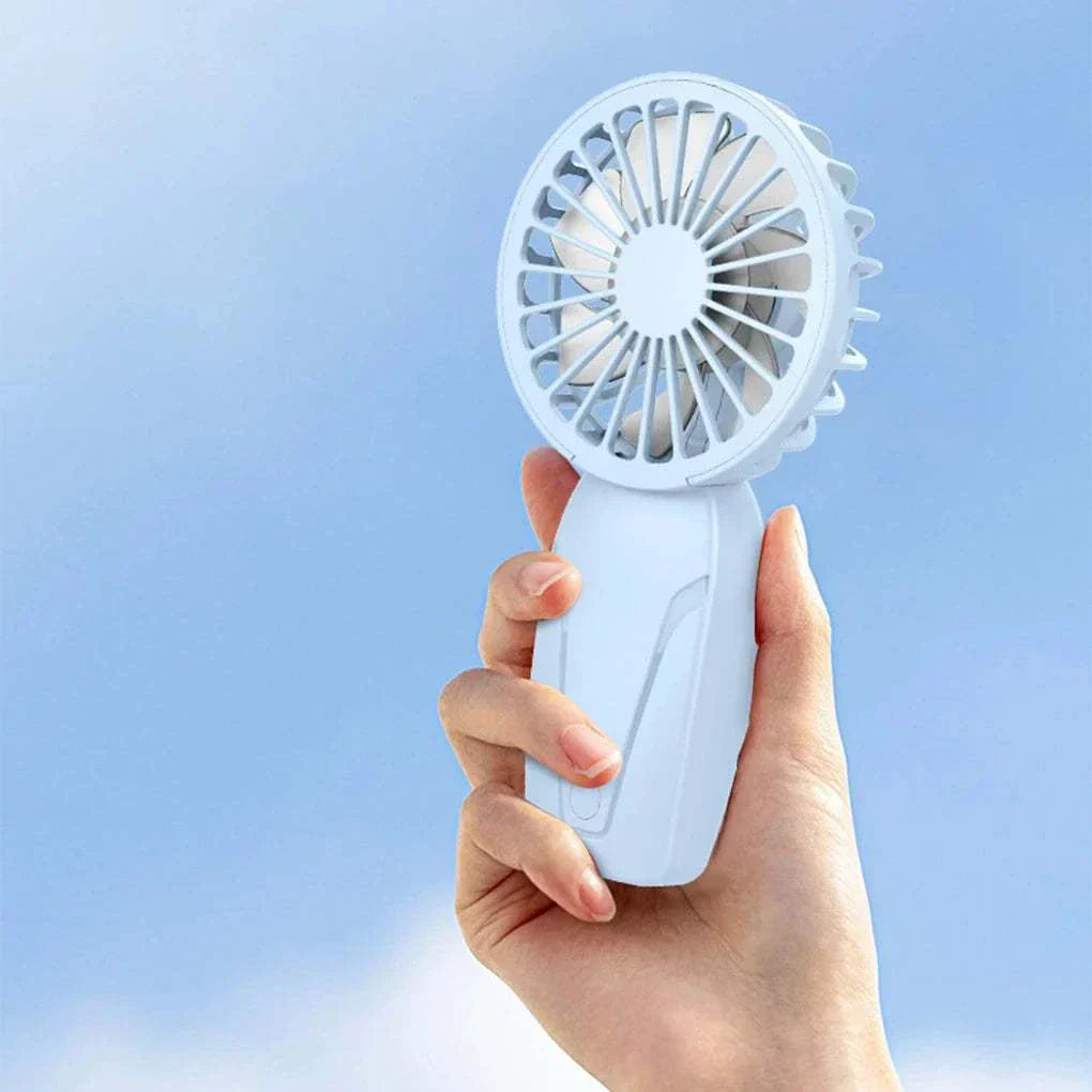 Hand holding a white cute portable handheld USB rechargeable fan against a blue sky background