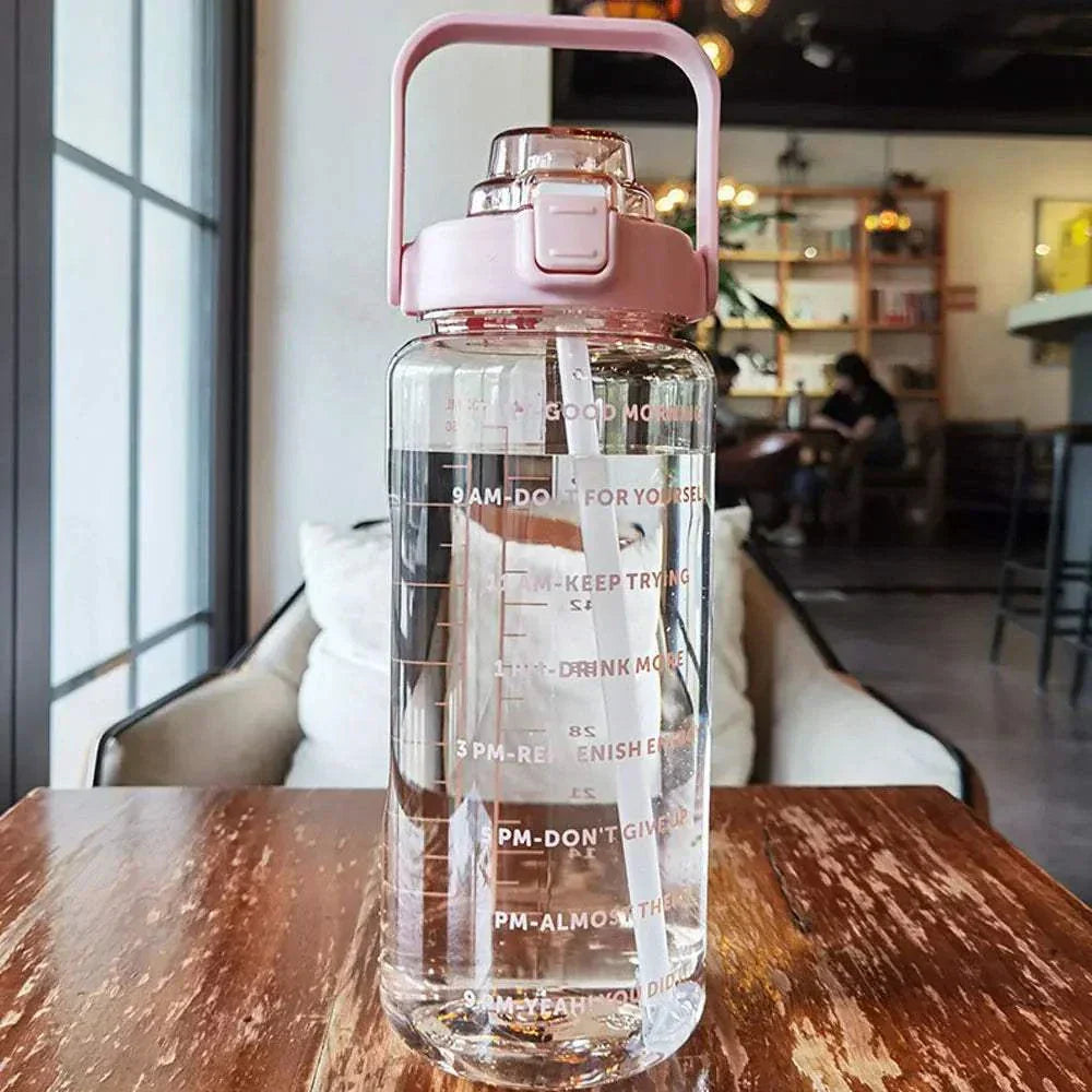 Transparent sports water bottle with pink lid, straw, and motivational time marker quotes for daily hydration tracking