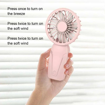 Cute portable handheld USB rechargeable fan in pink held in hand with three-speed wind power settings for on-the-go cooling
