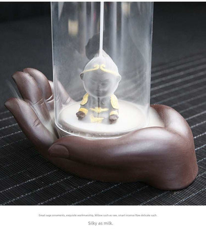 Backflow purple sand incense burner with ceramic Buddha hand holding glass lotus on dark surface